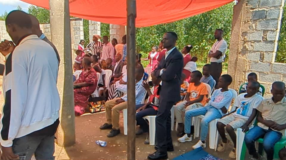 Children and adults listening during an outdoor church service